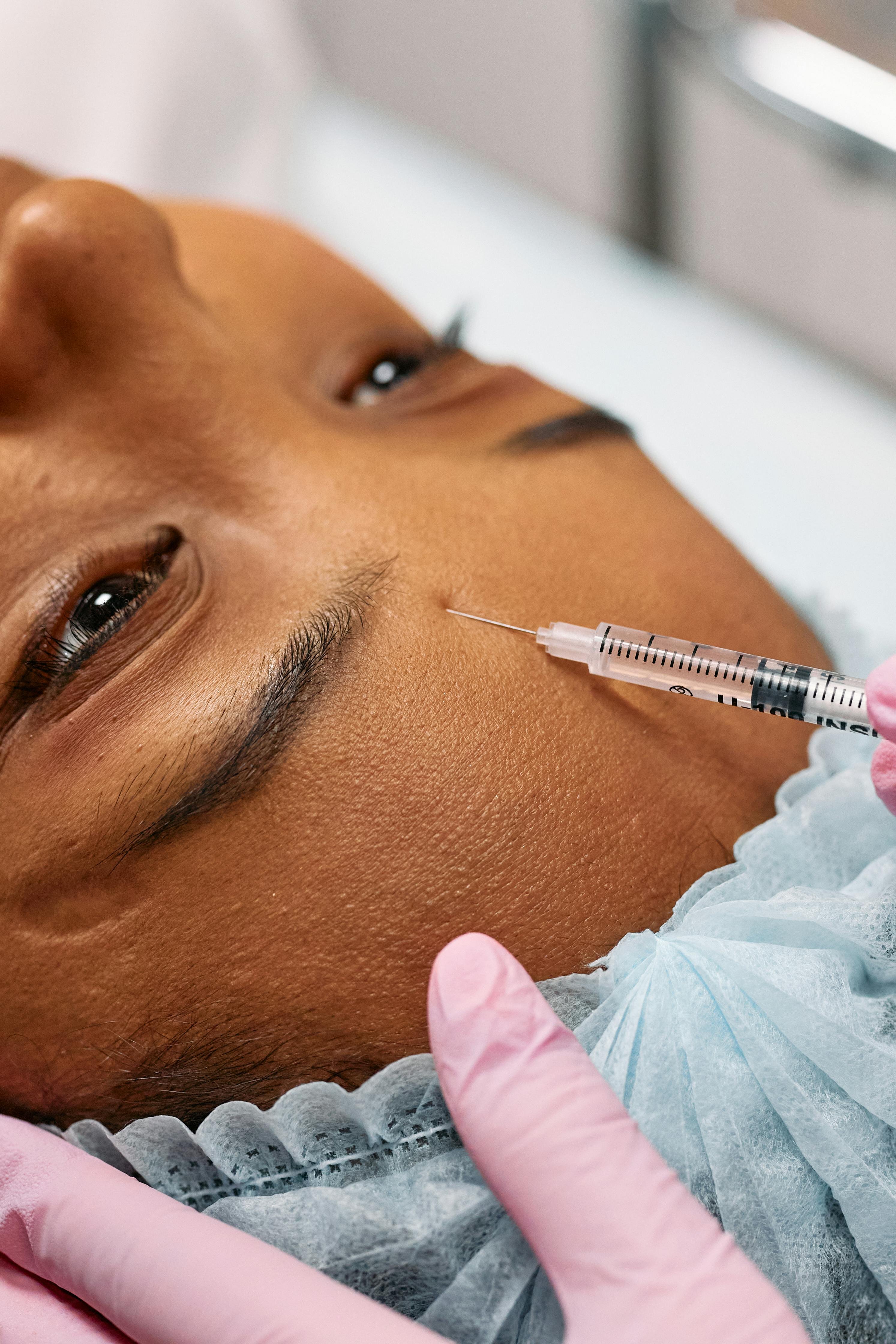 A patient receiving a cosmetic injection near the brow