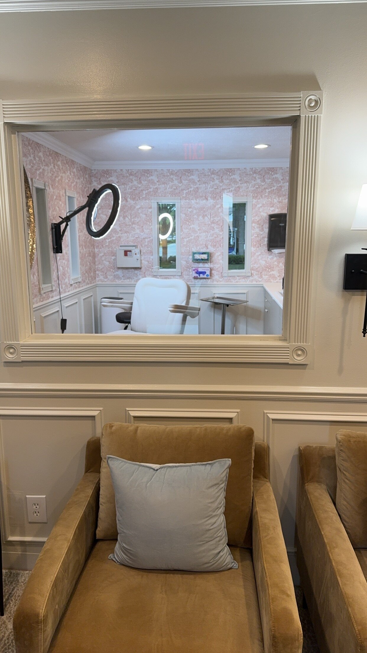 Treatment room viewed through an interior window at Glammed Up Aesthetics